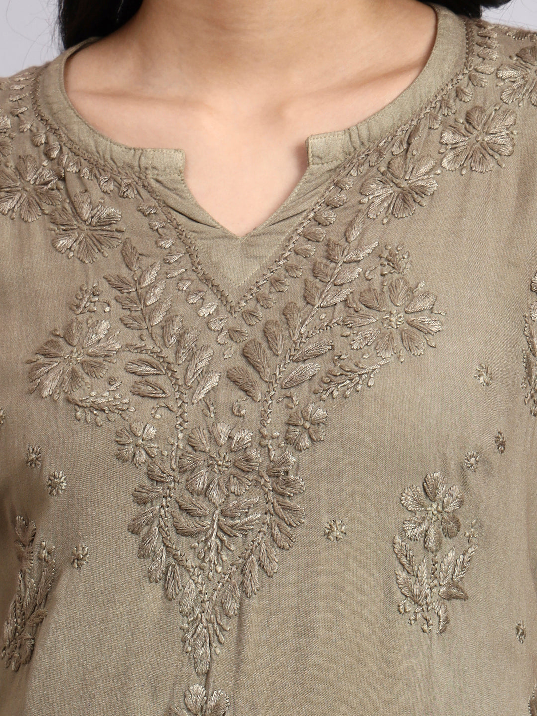 Close-up of a green embroidered garment with intricate patterns.