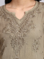 Close-up of a green embroidered garment with intricate patterns.