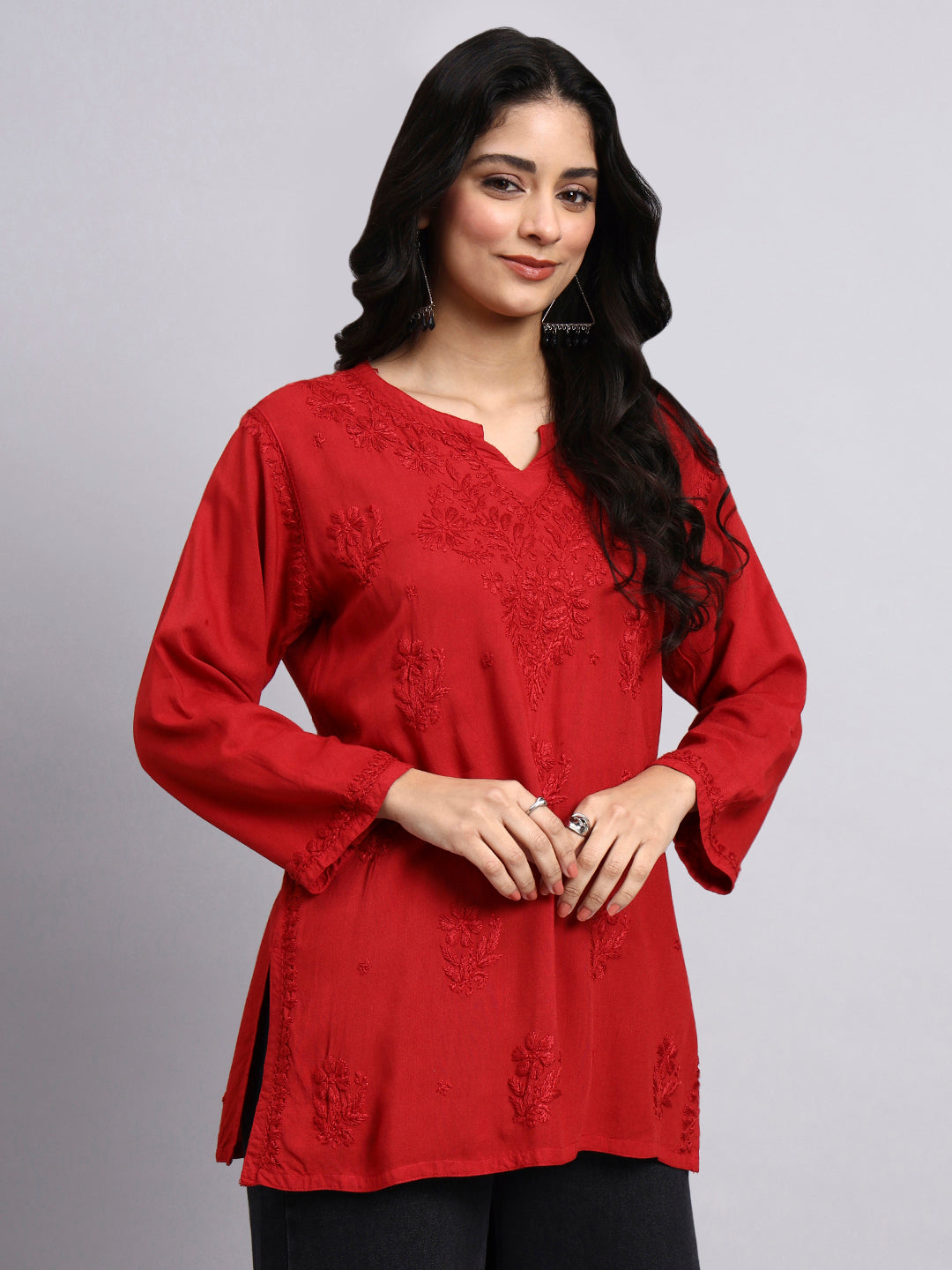 Woman wearing a red chikankari kurtaagainst a gray background