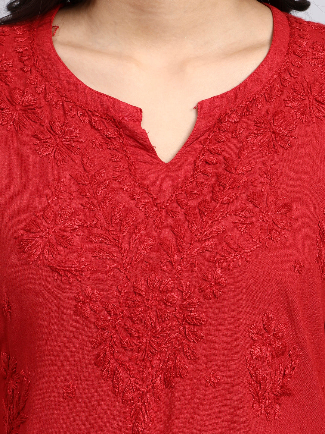 Close up of Red embroidered top with intricate patterns on a plain background