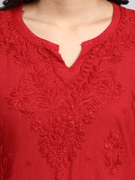 Close up of Red embroidered top with intricate patterns on a plain background