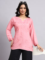 Front view of Woman wearing a pink embroidered top against a gray background
