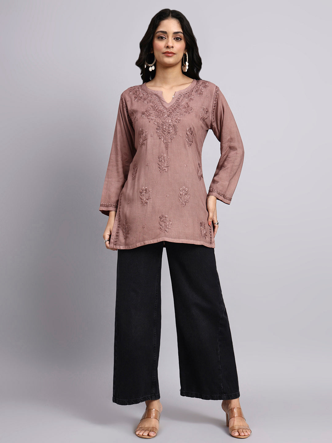 Front view of Woman wearing a brown embroidered top and black pants on a gray background