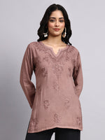 Woman wearing a mauve embroidered chikankari short kurta against a gray background