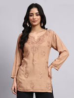 Front View of Woman wearing a beige embroidered Chikankari Kurta against a gray background