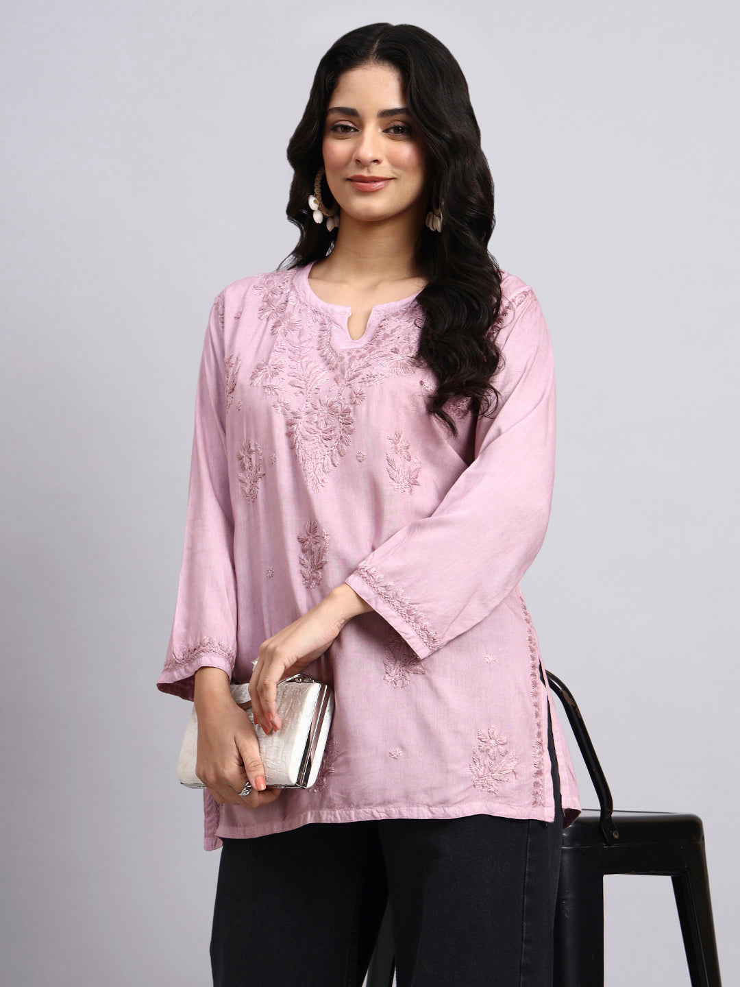 Woman wearing a light pink short chikankari kurta with lace details on a gray background