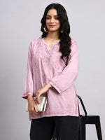 Woman wearing a light pink short chikankari kurta with lace details on a gray background