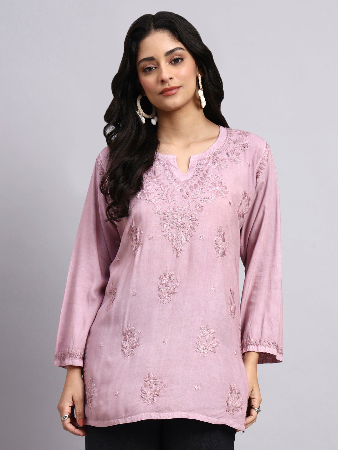 Woman wearing a pink embroidered kurta against a gray background